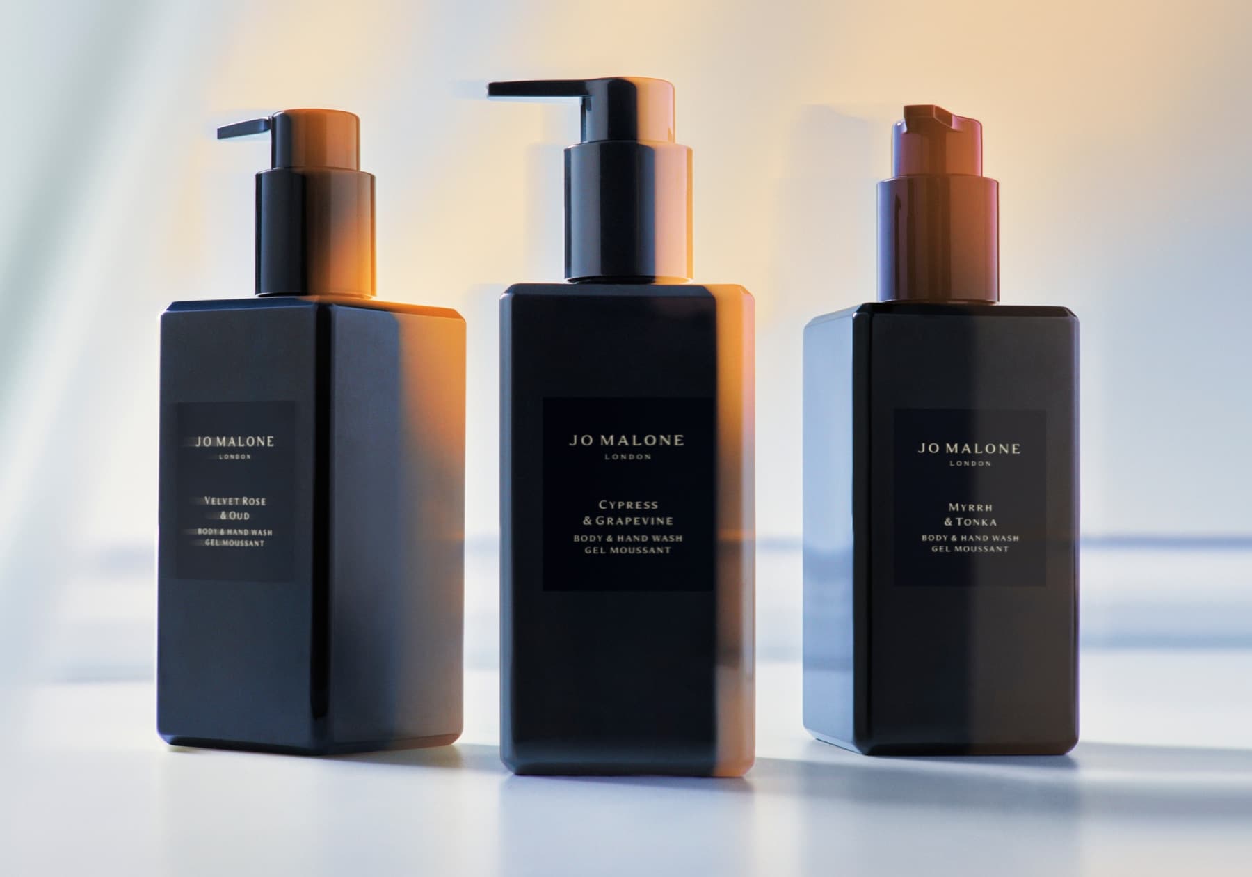 Three Cologne Intense body and hand washes atop a table. The dark bottles, with a pump, stood in a line are slightly blurred.