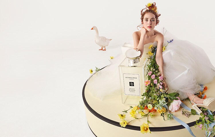 Image of a wedding dining table covered in flowers & candles with jo malone boxes on the plates for wedding favours